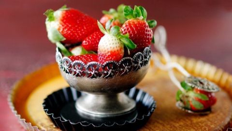 Frische Erdbeeren liegen in einer dekorativen Schale auf einem rustikalen Holzbrett, ideal für eine Erdbeer-Bowle.