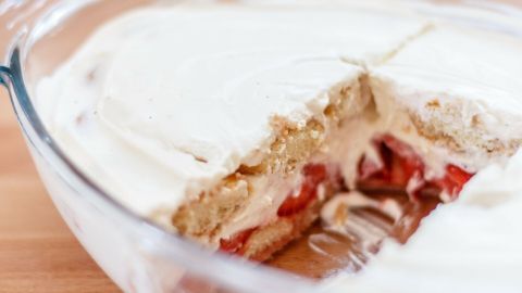 Ein cremiges Erdbeer-Tiramisu mit einer Schicht aus frischen Erdbeeren und Löffelbiskuits in einer Glasschüssel.