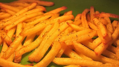 Knusprige Backofenpommes liegen auf einem grünen Teller und warten darauf, serviert zu werden.