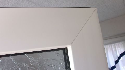 Der Kunststoffrahmen einer Tür wird sorgfältig gereinigt, um die Oberfläche zu erhalten. Im Hintergrund ist ein Fenster sichtbar.