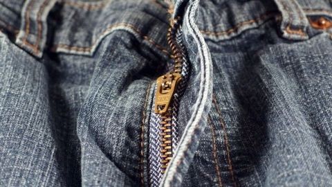 Eine beschädigte Jeans mit offenem Reißverschluss zeigt, dass der Reißverschluss kaputt ist und repariert werden kann.