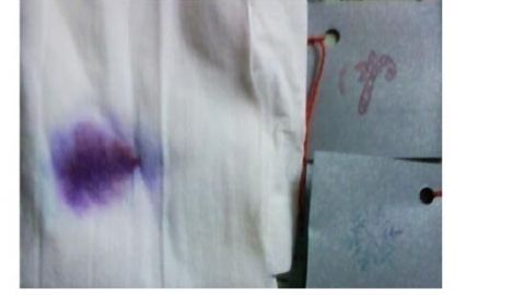 Ein lila Stempelkissen hinterlässt einen Abdruck auf einem weißen Stoff, daneben eine graue Karte mit weiteren Drucken.
