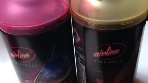Zwei automatische Duftspender stehen nebeneinander auf einer Oberfläche, einer hat eine pinke und der andere eine gelbe Kappe.