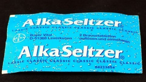 Ein blaues Alka-Seltzer-Päckchen liegt auf einem schwarzen Hintergrund, bereit zur Einnahme bei Blasenentzündung.