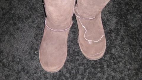 Zwei braune Wildleder-Stiefel stehen auf einem dunklen Teppich, bereit zur Reinigung von Salzrändern mit Zwiebeln.