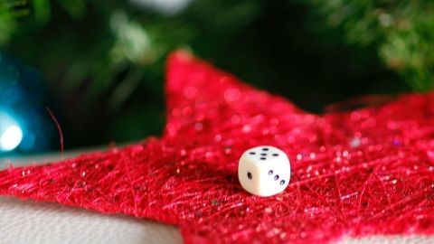 Auf einem roten Stern liegt ein Würfel, der das Auswürfeln von Geschenken in einem festlichen Weihnachtsumfeld symbolisiert.
