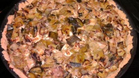 Quiche mit knusprigem Rand liegt frisch gebacken in einer Metallform, gefüllt mit goldbraunem Lauch und Thunfisch.
