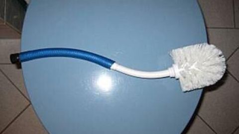 Eine gebogene Klobürste steht auf einer blauen Toilette und wird zur Reinigung verwendet, um den Geruch zu beseitigen.