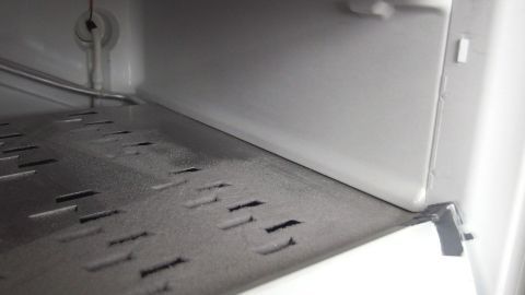 Ein Gefrierfach mit Eisablagerungen wird abgetaut, während Wassertropfen sich am Boden sammeln.