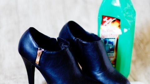 Schwarze Schuhe stehen neben einer grünen Flasche Spiritus, die zur Verhinderung von Druckstellen genutzt wird.