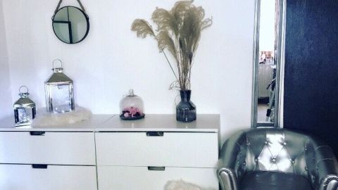 Ein silberner Sessel steht neben einer modernen Kommode, umgeben von Deko-Elementen in einem stilvollen WG-Zimmer.