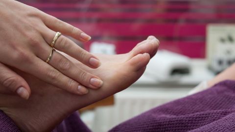 Eine Hand berührt sanft einen Fuß, während entspannende Umgebung den Heilungsprozess von Nagelpilz unterstützt.
