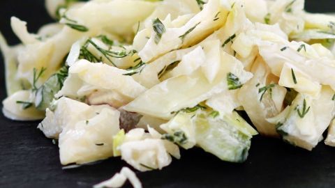 Feiner Rohkost-Weißkohlsalat liegt frisch zubereitet auf einem dunklen Untergrund und zeigt die knackigen Stücke.
