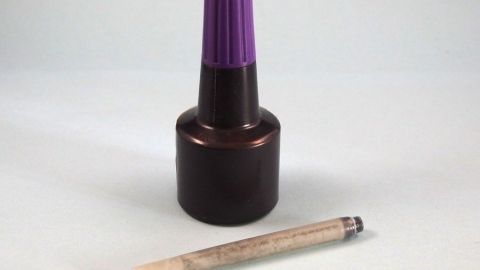 Ein Tintenfläschchen mit lila Deckel steht neben einer leeren Patrone, bereit zum Nachfüllen für den Tintenverbrauch.