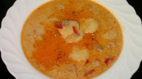 Eine schüssel mit Hackfleisch-Süppchen zeigt einen warmen, orange-farbenen Eintopf mit Gemüse und Fleischstückchen.