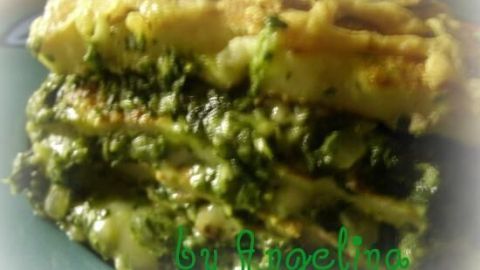 Eine Pfannkuchenlasagne ist zu sehen, mit abwechselnden Schichten aus Spinat und Käse, auf einem Teller. Text: "by Angelina".