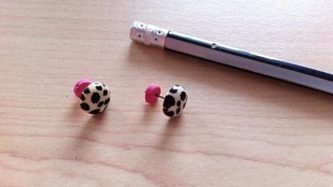 Auf einem Holztisch liegen zwei Ohrstecker mit Punkten, die neben einem Bleistift liegen, bereit zur Verwendung.