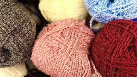 Bunte Strumpfgarne liegen übereinander und bieten eine Vielfalt an Farben für das Stricken von Kindersachen.
