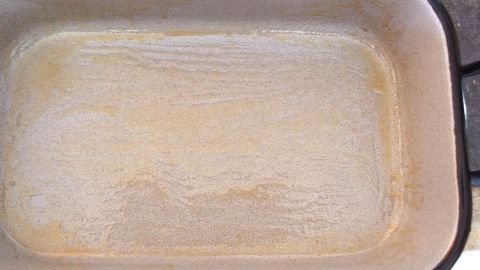 Eine gefettete Auflaufform liegt auf einer Arbeitsfläche, bereit zum Backen, mit einer gleichmäßigen Ölschicht.