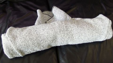 Ein zusammengerolltes Kleidungsstück liegt auf einer dunklen Oberfläche. Die Technik des Zusammenrollens spart Platz beim Kofferpacken.