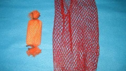 Ein orangefarbener Körper und ein rotes Netz liegen auf einem blauen Stoff, bereit für das Peeling der Haut.
