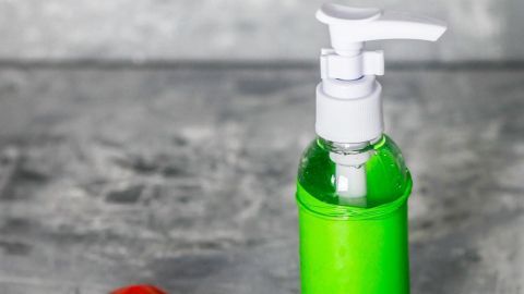Eine grüne Flasche mit Pumpkopf steht neben einem roten Luftballon, der zum Schutz der Flasche verwendet wird.