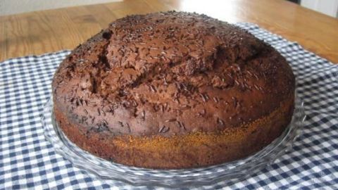 Ein runder, zarter Pfefferminz-Schokoladen-Kuchen steht auf einem karierten Tuch in einer gemütlichen Umgebung.