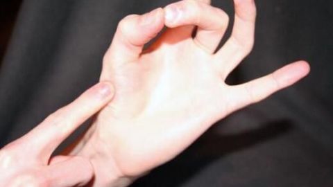 Eine Hand drückt mit einem Finger auf die Fläche der anderen Hand, als ob sie Garstufen von Steaks prüfen würde.