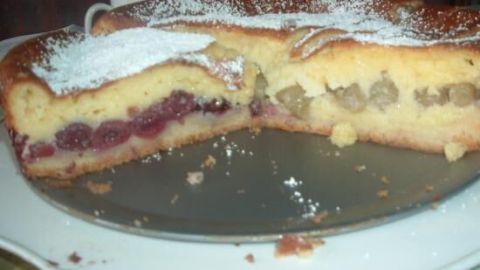 Ein geschnittener Kuchen auf einem Teller zeigt ein köstliches Inneres mit Früchten, perfekt für viele Gäste.