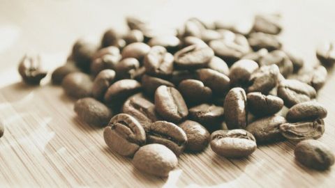 Kaffeebohnen liegen verstreut auf einer Holzoberfläche, um muffigen Trockner-Geruch zu neutralisieren.