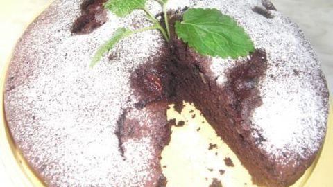 Der schokoladige Bananenkuchen liegt auf einem Teller, mit einer Schnittfläche und dekorativen Puderzucker und einem Blatt.