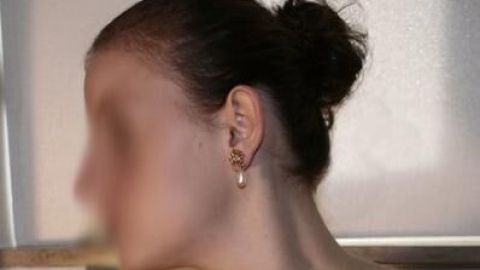 Ein Haarspray wird verwendet, um einen strengen Knoten zu fixieren, während sich die Person in einem hellen Raum befindet.