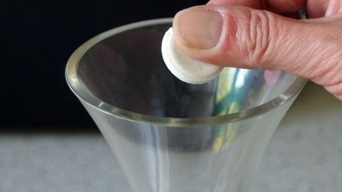 Eine Hand platziert eine Reinigungstablette in eine Glaskaraffe, um Weinränder zu entfernen.