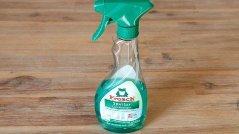 Eine Flasche Fensterputzmittel steht auf einem Holzuntergrund, bereit, um Ameisen fernzuhalten.