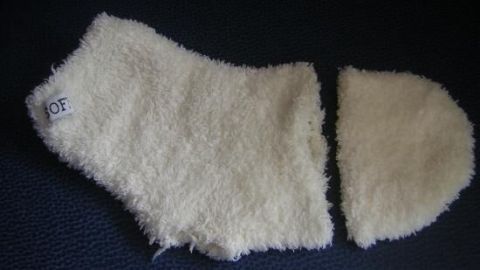 Ein zerlegter weißer Socken liegt auf dunklem Hintergrund. Ein Teil des Socken hat ein Etikett mit der Aufschrift "OF".