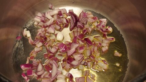 In einem Topf braten kleine, gehackte Zwiebeln in Öl an, um Geschmack zu entwickeln.