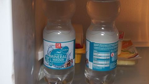 Gekühlte Getränkeflaschen stehen nebeneinander in einem Kühlschrank und warten darauf, entnommen zu werden.