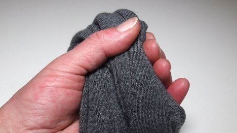 Eine Hand hält eine graue Kinderstrumpfhose fest, während der Fokus auf der Verwendung von Strumpfhosen liegt.
