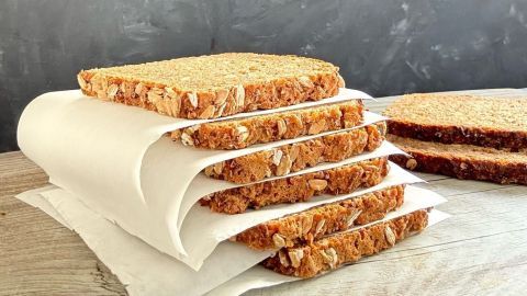 Schwarzbrot clever einfrieren: Lege Backpapier zwischen die Scheiben, um sie einzeln zu entnehmen und Abfall zu vermeiden. So bleibt dein Brot länger frisch und du kannst bei Bedarf einzelne Portionen auftauen.