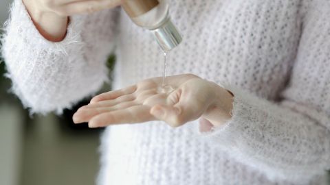 Mildes Haarshampoo oder Kinderhaarshampoo mit Wasser verdünnt ergibt eine schonende Seife. Eine Person mit einem weichen, flauschigen Pullover gießt mildes Haarshampoo in die Handfläche, um es als Seife zu verwenden.