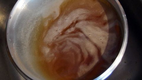 Eine dampfende Mischung in einem metallischen Topf bewegt sich, während das heiße Getränk abkühlt.