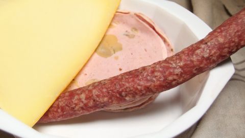 Einweg-Suppenschüsseln enthalten Reste: Wurst, Aufschnitt und Käse sind in einer Schüssel angeordnet.