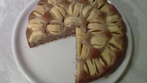 Ein Kuchen ohne Ei und ohne Mehl auf einem weißen Teller, mit einer Kante, die bereits angeschnitten ist.