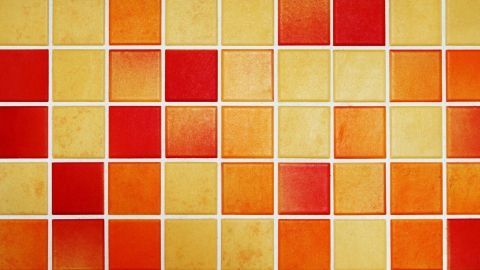 Bunte Fliesen mit orange, gelben und roten Mustern bilden die Oberfläche, die für die Reinigung von Schimmelfugen genutzt wird.