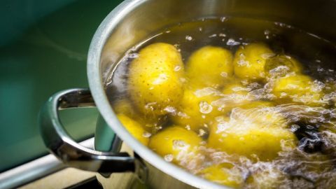 Im Topf kochen Pellkartoffeln sprudelnd in Wasser, umgeben von einer modernen Küchenumgebung.