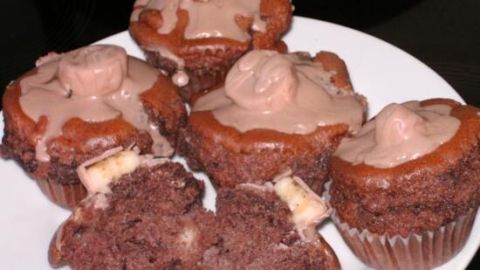 Fünf saftige Schoko-Bananen-Muffins liegen auf einem weißen Teller und sind mit einer schokoladigen Glasur dekoriert.
