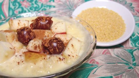 Ein Schüsselchen mit fruchtigem Hirsefrühstück steht auf einem bunten Tisch, daneben ist eine Schale mit Hirse.