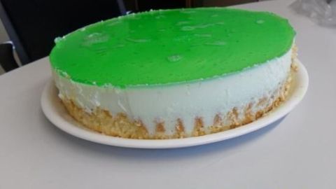 Waldmeister-Torte ruht auf einem weißen Teller, zeigt eine grüne Gelee-Schicht oben, umgeben von Büromöbeln. Text: "2011/07/07 07:14 AM".