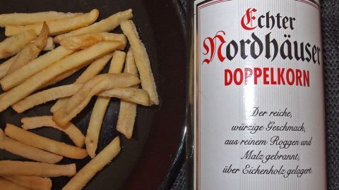 Frittierte Pommes frites liegen neben einer Flasche Doppelkorn, um den Kater nach dem Alkohol zu bekämpfen.
