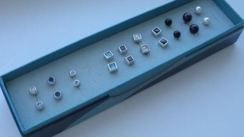 Ohrstecker sind ordentlich in einer blauen Box aufbewahrt, bereit für die nächste Verwendung auf einem Tisch.